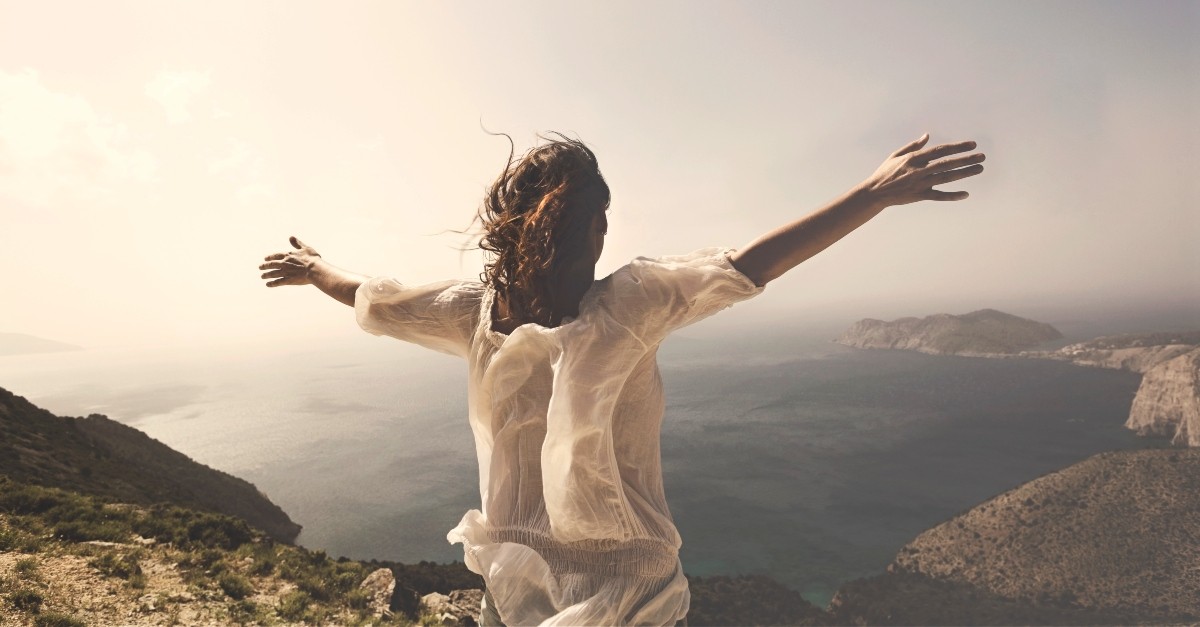 Woman with hands stretched over a mountainside